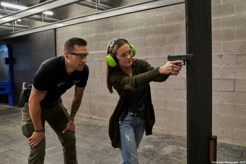 a woman being trained to shoot a gun for self defense.