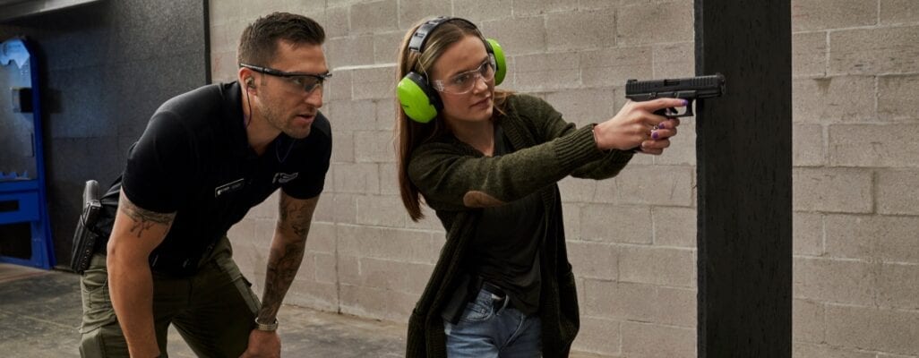 Qualification Is the Minimum, Not the Goal 3 a woman being trained to shoot a gun for self defense.