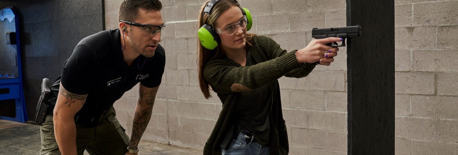 Qualification Is the Minimum, Not the Goal 2 a woman being trained to shoot a gun for self defense.